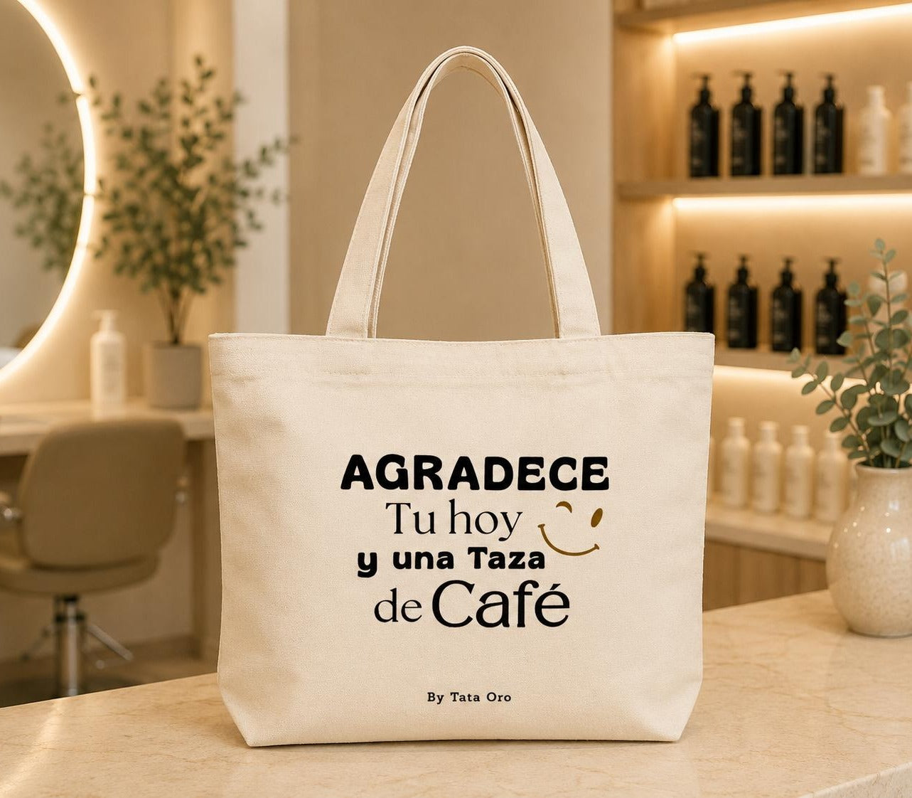Natural canvas tote bag with Agradece Tu hoy y una Taza de Café design and gold winking smile, by Tata Oro